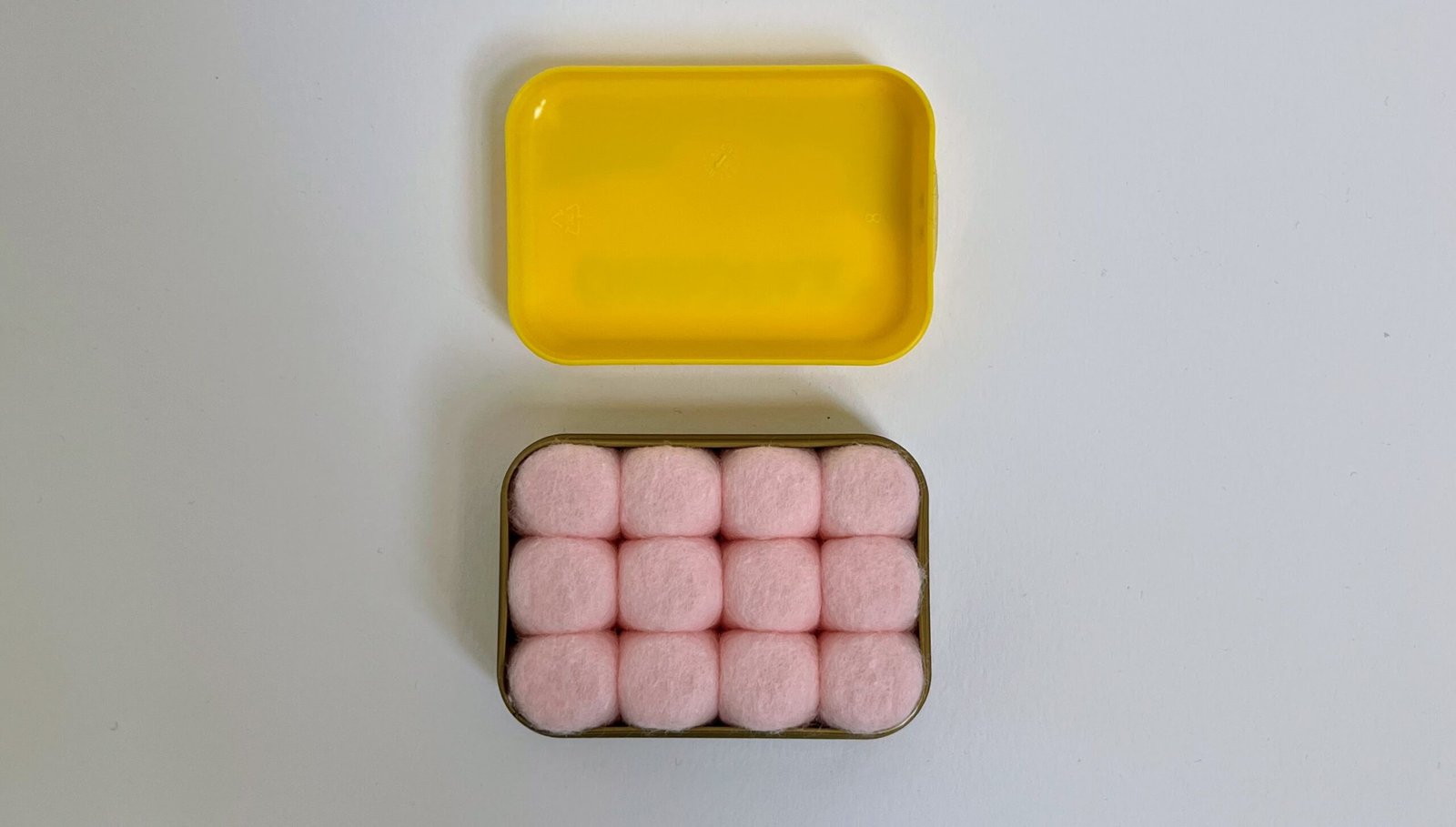 Ohropax wax earplugs, a soft ball of wax wrapped in cotton, photographed on a plain surface