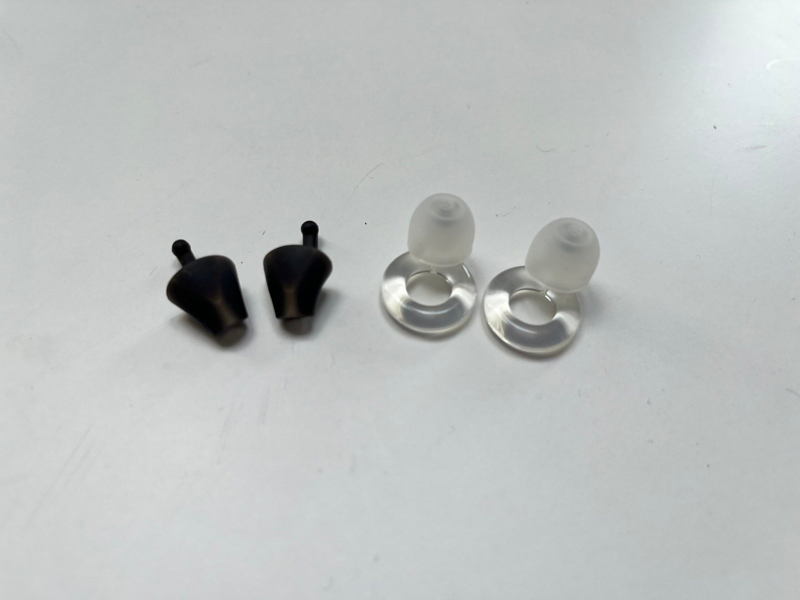 Flare Calmer Pro and Loop Engage earplugs side by side. The Calmer Pro is an open, stemless device that sits in the ear canal; the Loop Engage is a ring-stemmed plug that seals the canal.